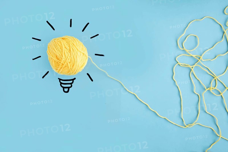 Illuminated yarn yellow light bulb blue background