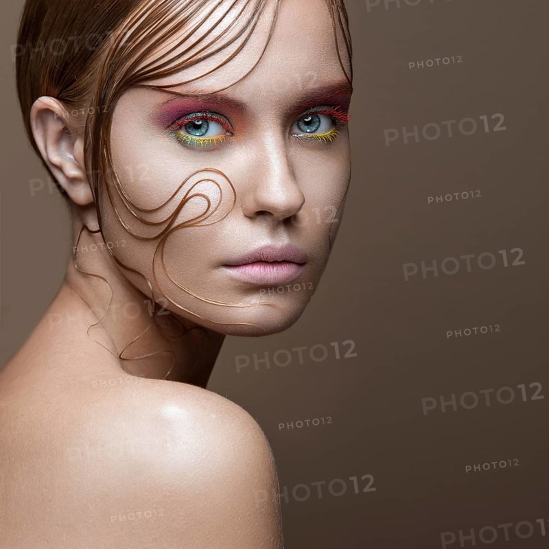 Beautiful girl with bright colored makeup and wet strands of hair on the face. Creative image. Picture taken in the studio
