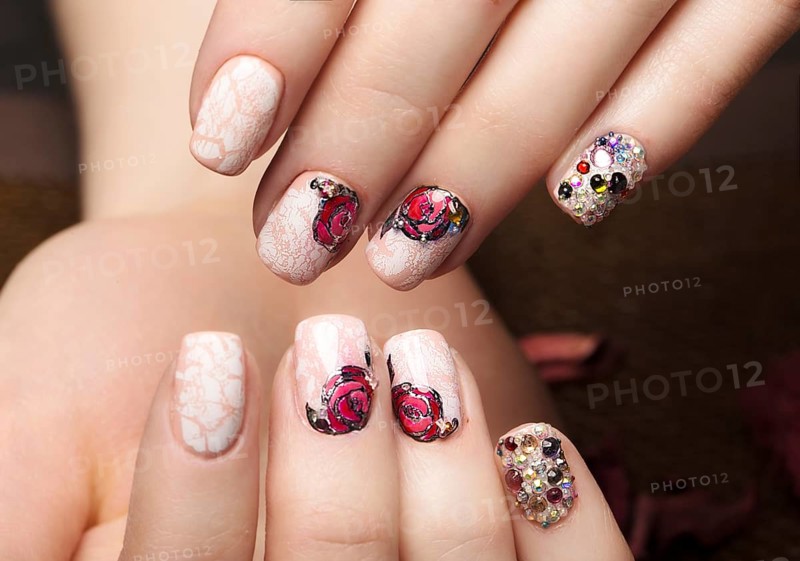 Beautiful manicure with flowers on female fingers. Nails design. Close-up. Picture taken in the studio on a white background