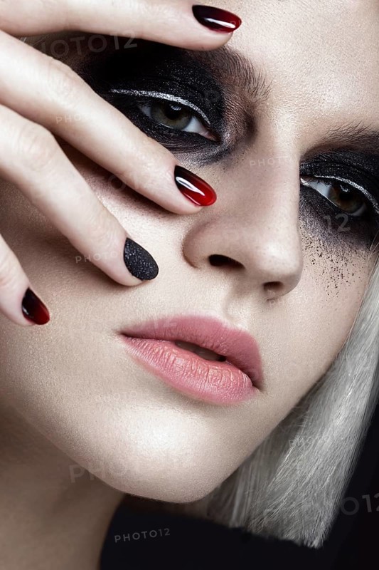 Beautiful blond girl with dark smokey makeup and art manicure design nails. beauty face. Photos shot in studio