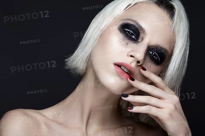 Beautiful blond girl with dark smokey makeup and art manicure design nails. beauty face. Photos shot in studio