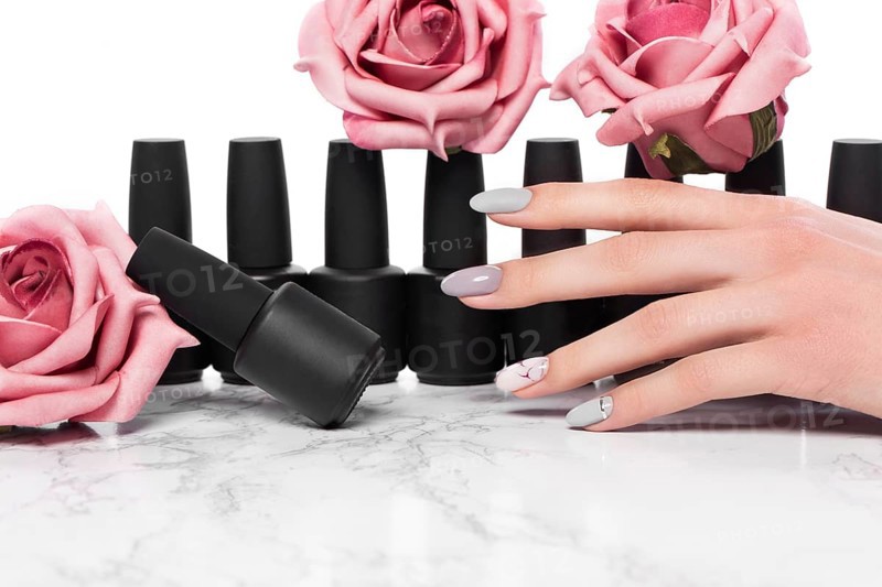 Black bottles of nail polish on a background of flowers. Manicure design