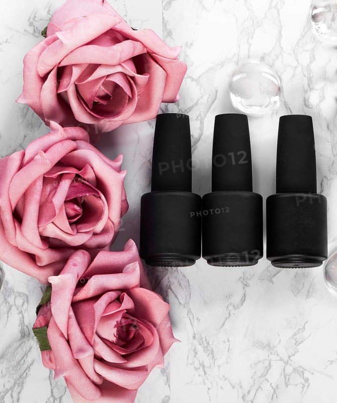 Black bottles of nail polish on a background of flowers. Manicure design