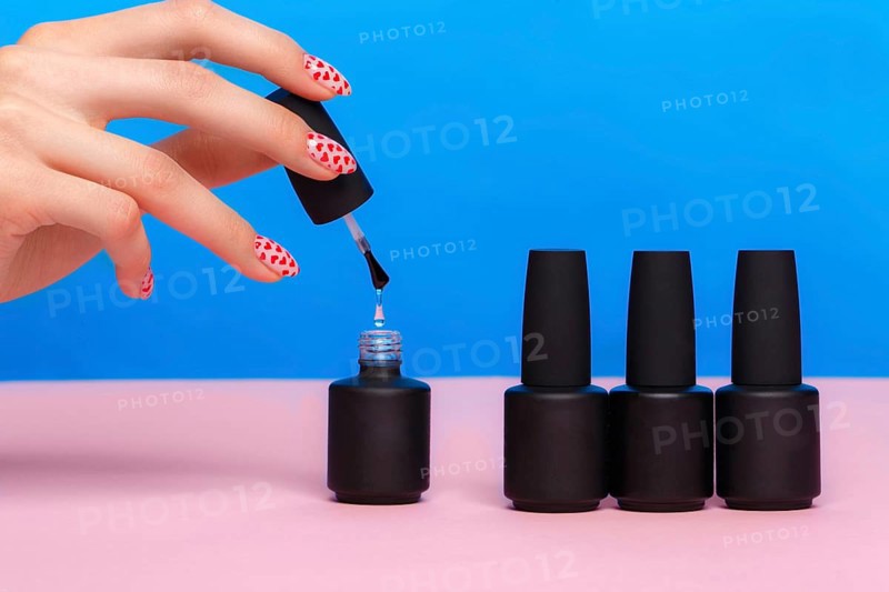 Black bottles of nail polish on a colorful background. Manicure design