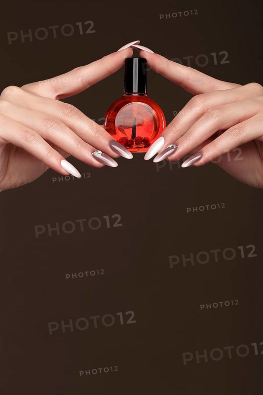 Beautiful classic manicure on female hand with oil for cuticles. Close-up. Picture taken in the studio