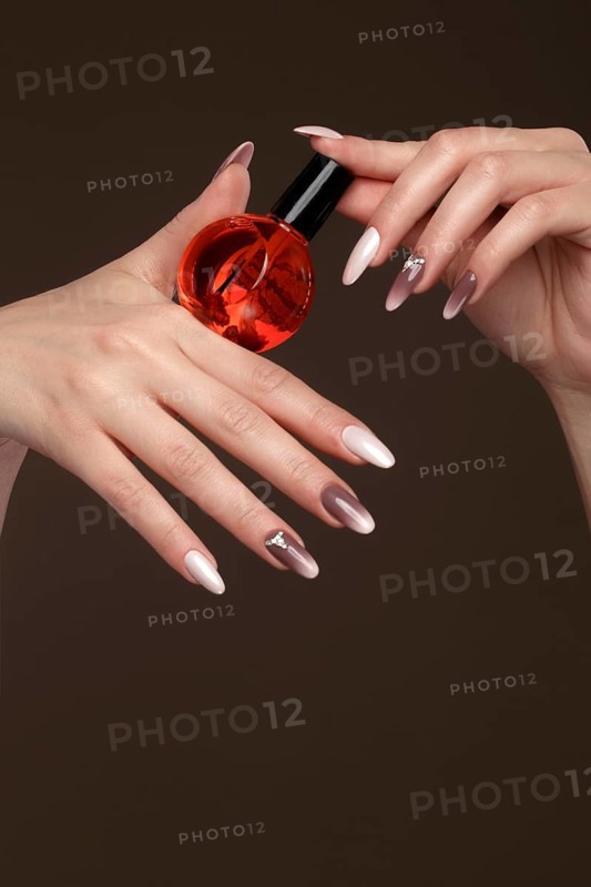 Beautiful classic manicure on female hand with oil for cuticles. Close-up. Picture taken in the studio