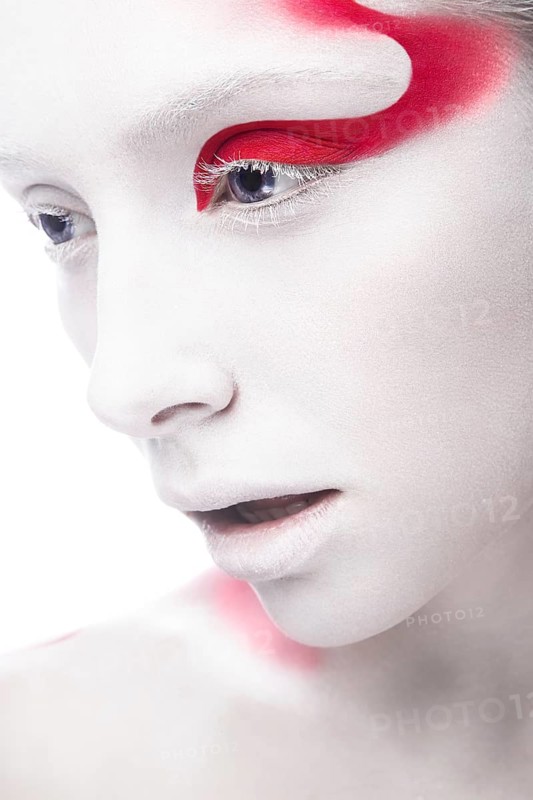 Art fashion girl with white skin and red paint on the face. Creative art beauty. Picture taken in the studio on a white background