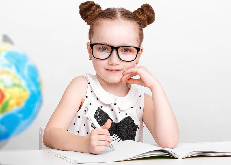 Little girl at the table of a first-grader. Photo taken in the studio