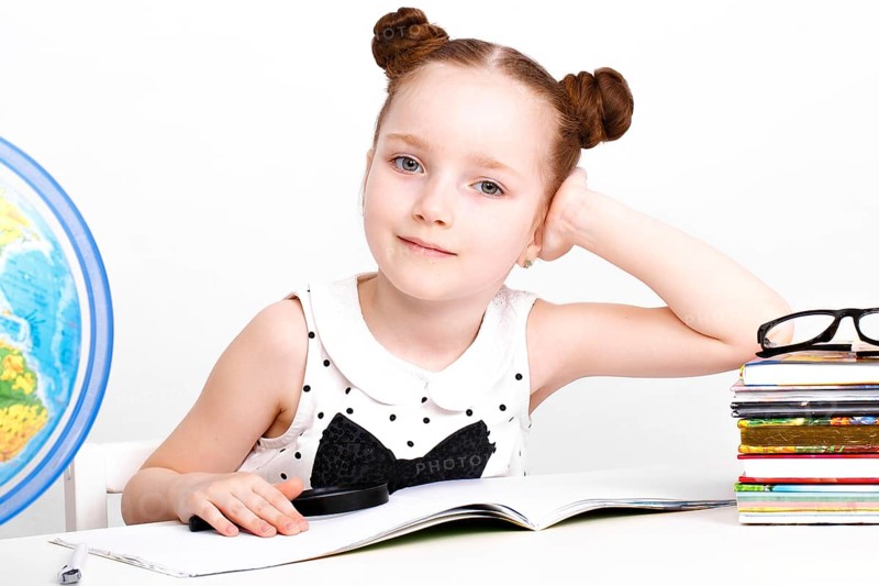 Little girl at the table of a first-grader. Photo taken in the studio