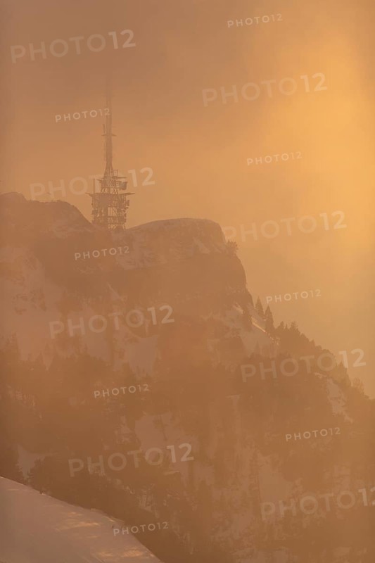 The transmission tower in the fog and warm light of the setting sun
