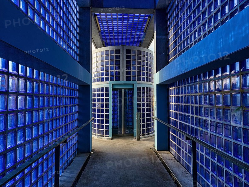 Access to the S-Bahn platform with lift made of blue glass blocks and exposed concrete