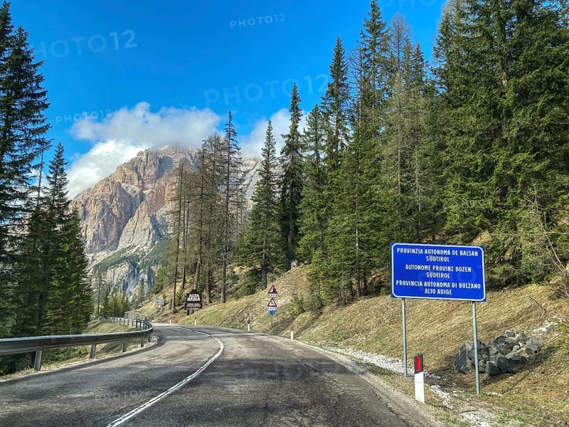 Mountain road behind Passo di Valparola with view of sign marking border between Veneto and Province of Bolzano South Tyrol
