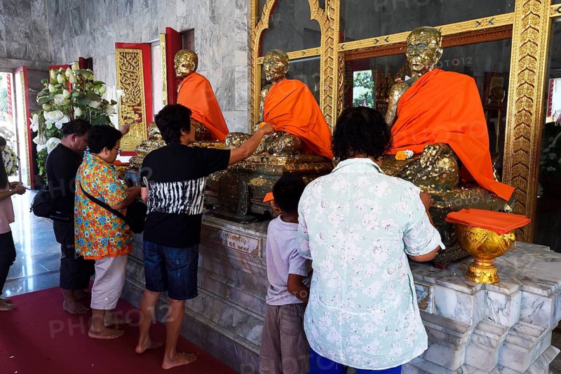 Believers cover statues of monks with gold leaf