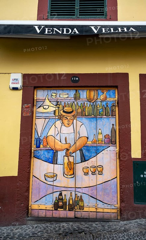 Colourfully painted door with bartender preparing poncha