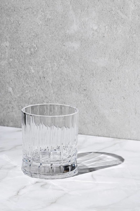 Empty facetted glass over grey background