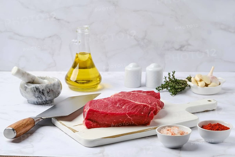 Raw top side beef steak with spice and herbs on kitchen table
