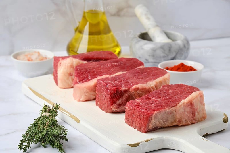 Closeup view of raw beef brisket flat steak on white wooden cutting board