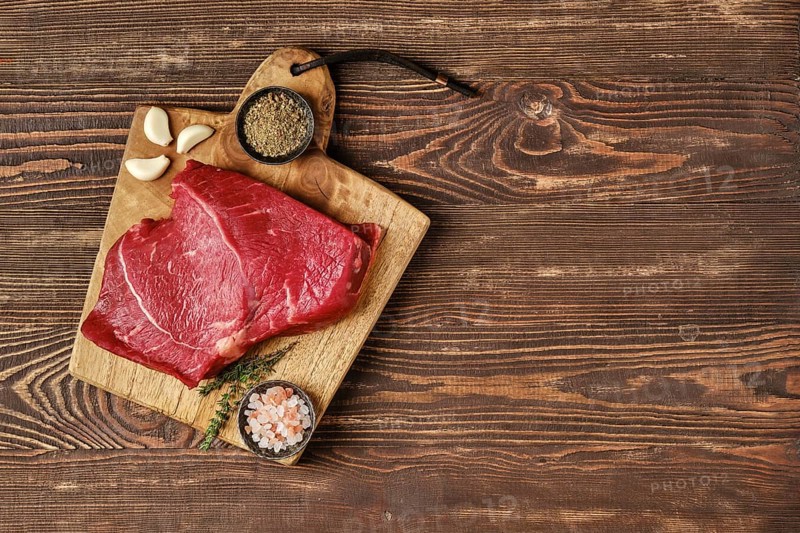 Overhead view of raw top side beef steak on wooden tabletop with place for text
