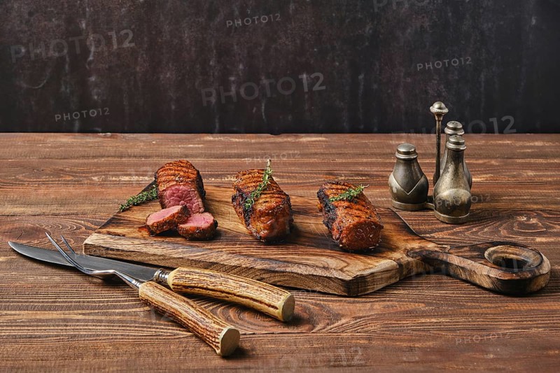 Grilled beef brisket flat steaks on wooden serving board