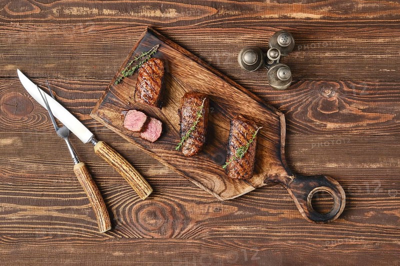 Top view of grilled beef brisket flat steaks on wooden serving board