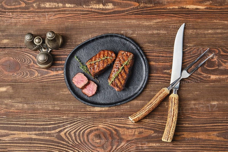 Top view of grilled beef steaks on wooden serving board