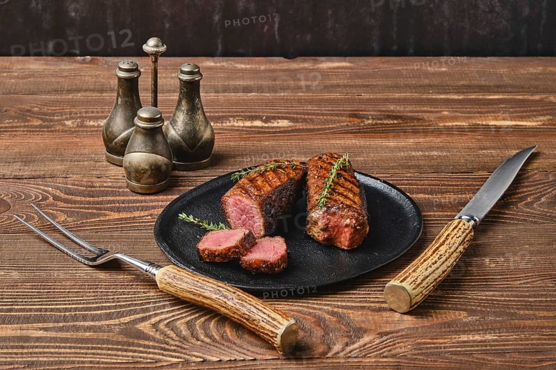 Roasted beef steak cut on slices on black plate