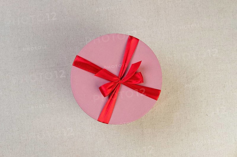 Round pink giftbox with red ribbon