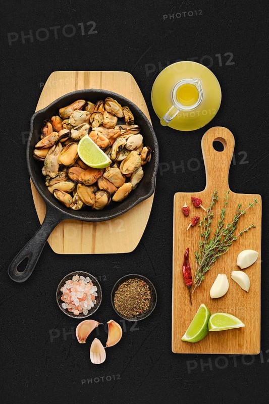 Boiled mussels and spice ready for frying on black background