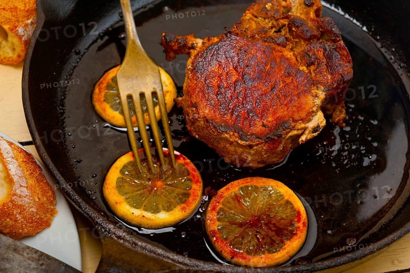 Pork chop seared on iron skillet with lemon and spices seasoning