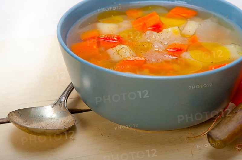 Traditional Italian minestrone soup on a rustic table with ingredients