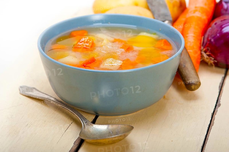 Traditional Italian minestrone soup on a rustic table with ingredients