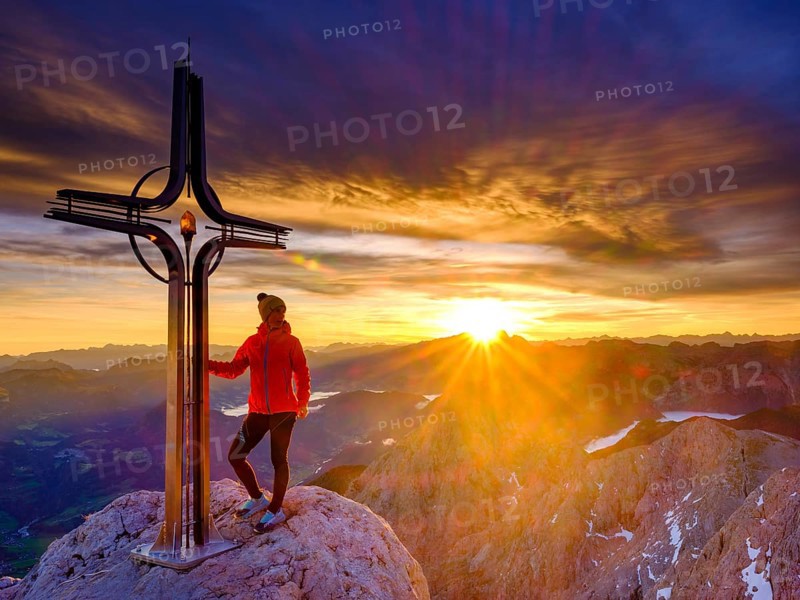 Mountaineer at the summit cross Hohe Goell at sunrise