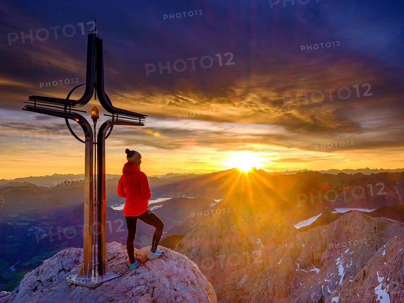 Mountaineer at the summit cross Hohe Goell at sunrise