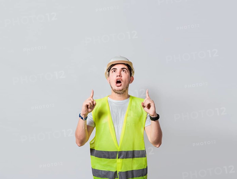Amazed engineer pointing at an advertisement. Concept of an engineer with astonished face pointing at blank space