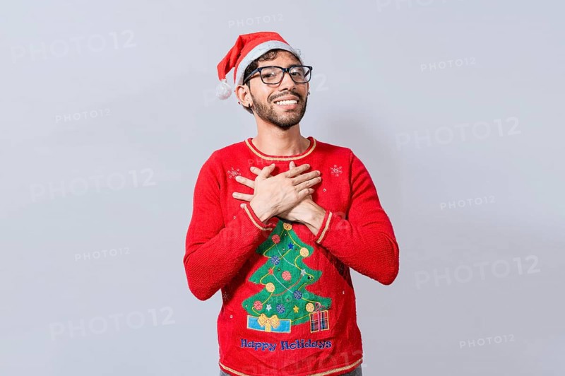 Thankful people in christmas clothes smiling with hands on chest. Man in christmas hat with sincere lovely smile feeling thankful