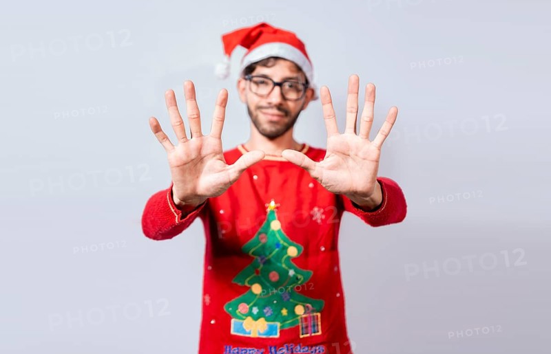 Man in christmas hat counting number ten with fingers. Christmas young man counting number ten with hands. Concept of man in christmas costume counting number ten isolated