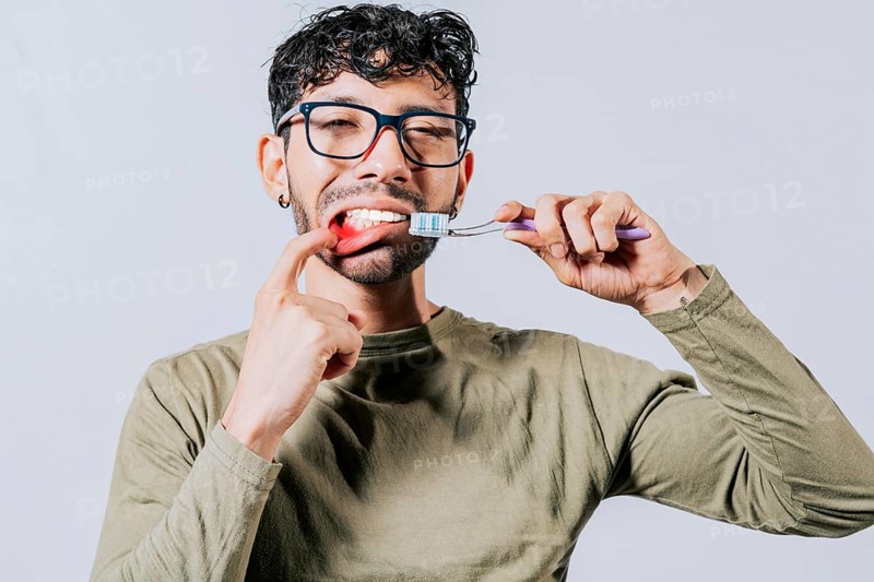 Man holding toothbrush with gum pain