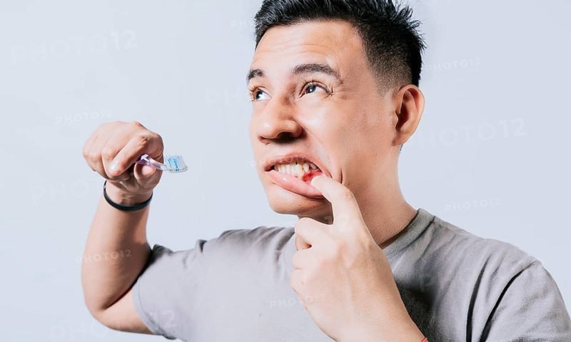 Man holding toothbrush with gum pain isolated