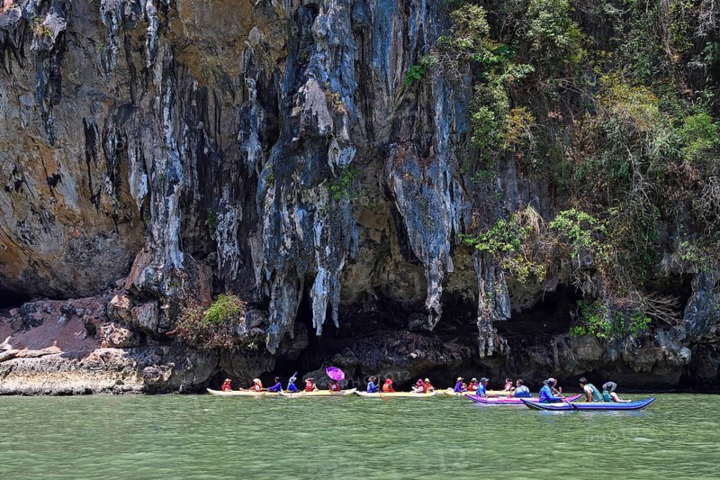 Tourists explore eroded limestone cliffs by canoe in Phang Nga Bay
