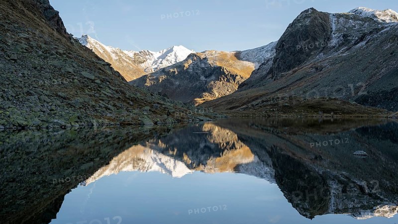 Slightly snow-covered mountains reflected in Schwarzsee in autumn on the Flueela Pass