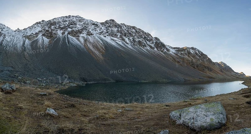 Lightly snow-covered mountains at Schottensee in autumn at the Flueela Pass