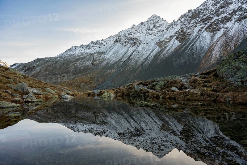 Lightly snow-covered mountains and mountain lake in autumn on the Flueela Pass