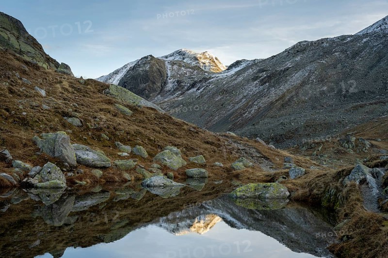 Lightly snow-covered mountains and mountain lake in autumn on the Flueela Pass