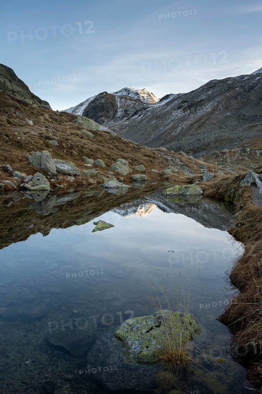 Lightly snow-covered mountains and mountain lake in autumn on the Flueela Pass