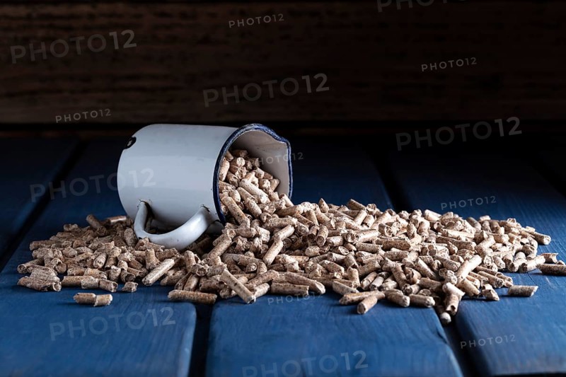 Wood pellets with enamel cup on blue wooden background