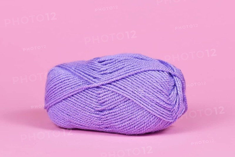 Single violet ball of wool on pink background