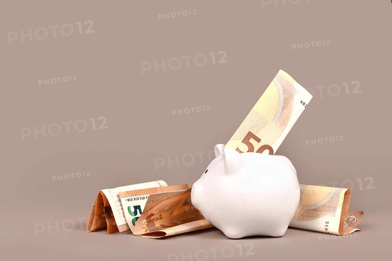 White piggy bank with 50 Euro bills on beige background with copy space. Concept for saving money