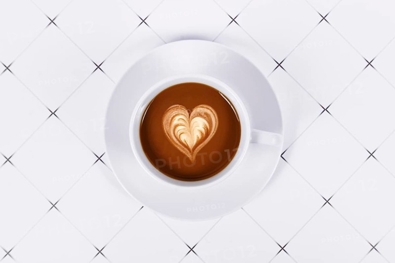Top view of cup of cocoa with heart shaped milk coffee art
