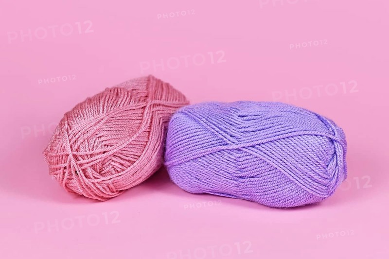 Two balls of wool on pink background