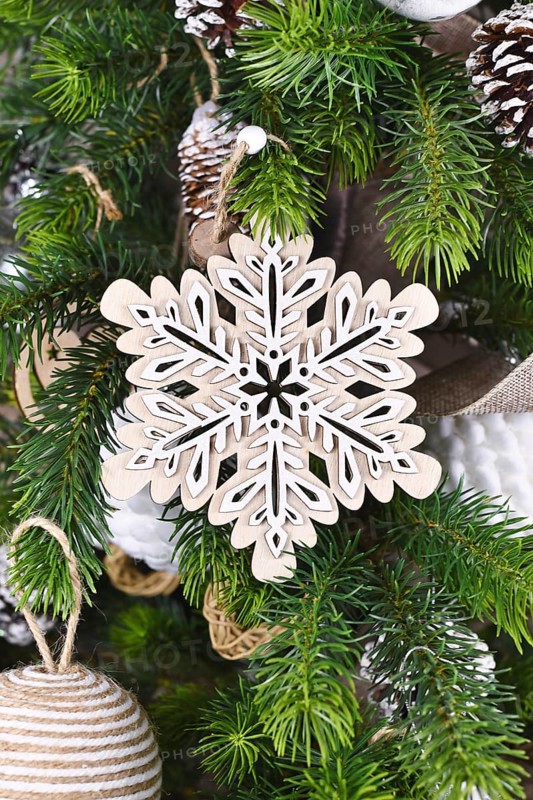 Christmas tree branch with natural wooden snowflake ornament